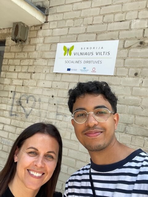 Specialistė Kristina ir praktikantas Wissam prie įėjimo į bendriją „Vilniaus Viltis“.